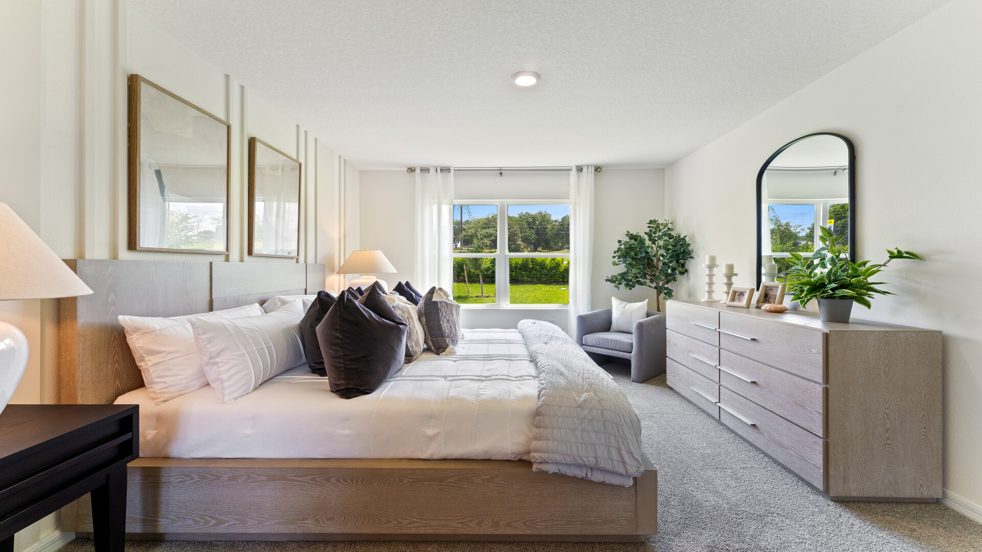 Spacious primary bedroom showing king sized bed, dressers and access to master bathroom.