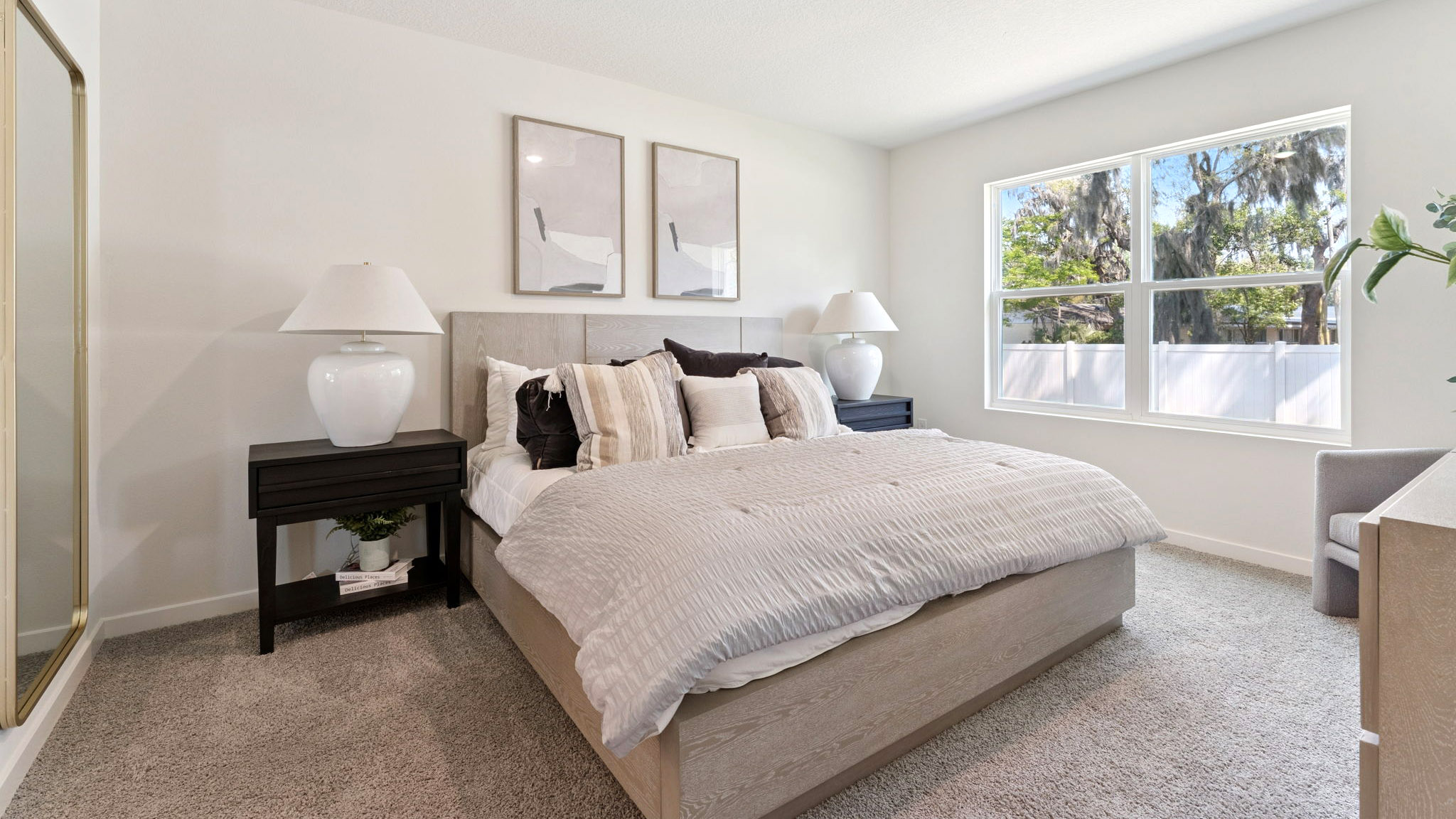 Spacious primary bedroom with king size bed, carpet flooring, natural lighting.