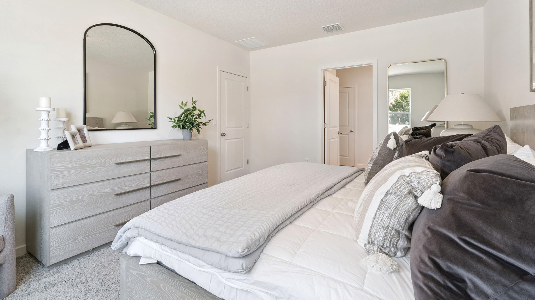 Spacious primary bedroom with king size bed, carpet flooring, natural lighting.