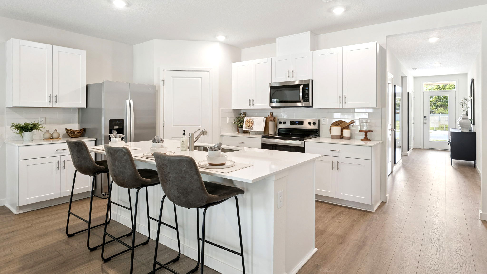 Kitchen with island seating, quartz counters, spacious pantry and stainless steel appliances.