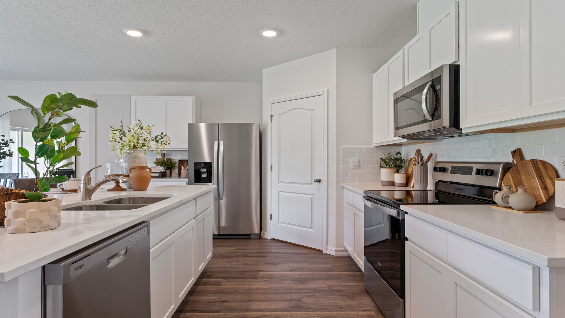 Kitchen with island seating, quartz counters, spacious pantry and stainless steel appliances.