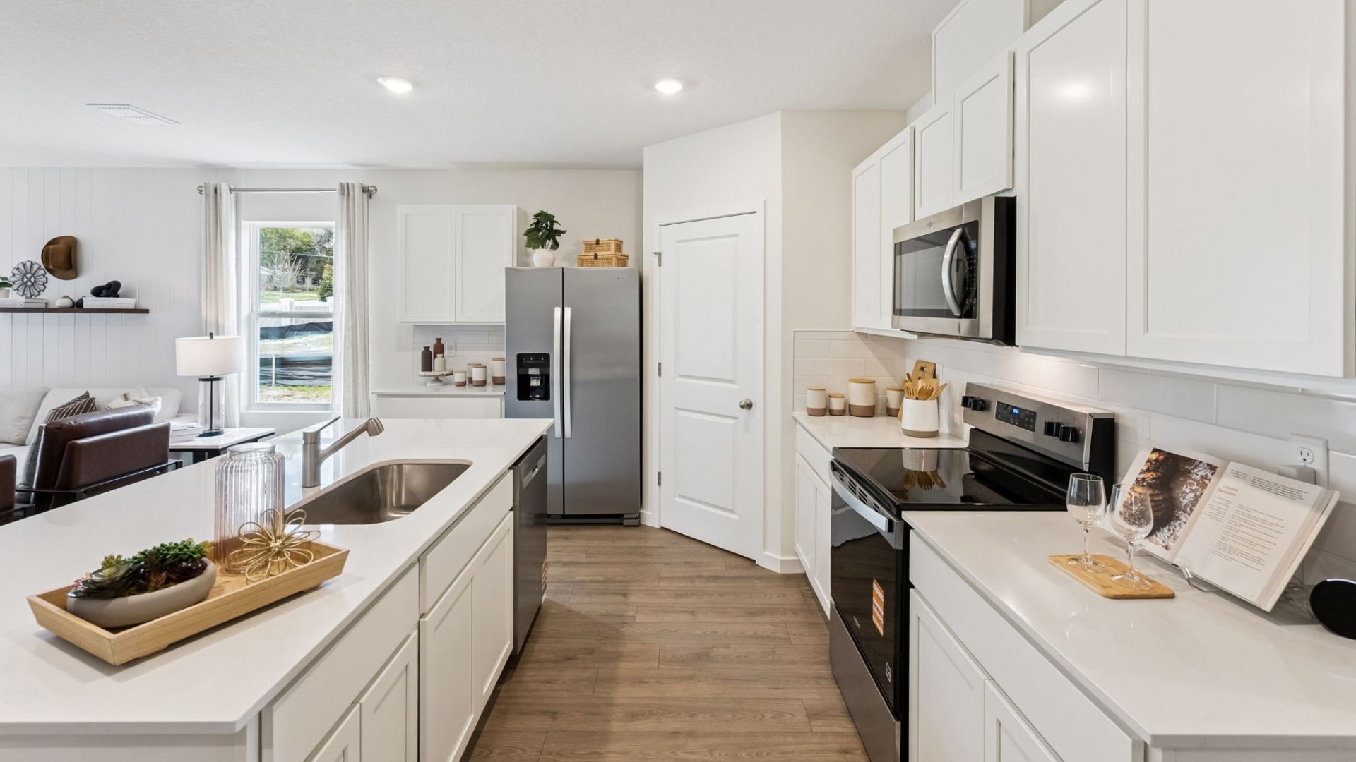 Kitchen with island seating, quartz counters, spacious pantry and stainless steel appliances.