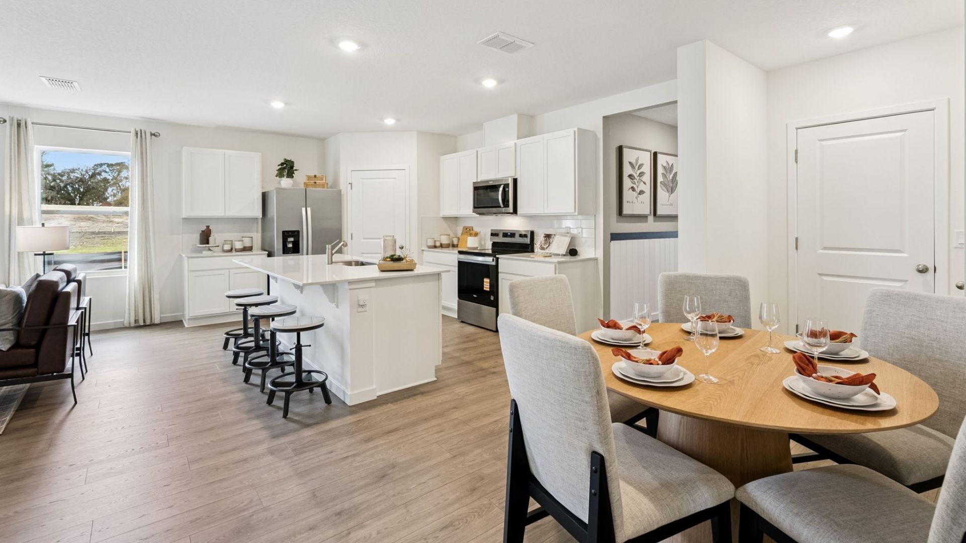 Kitchen with island seating, quartz counters, spacious pantry and stainless steel appliances overseeing dining room table