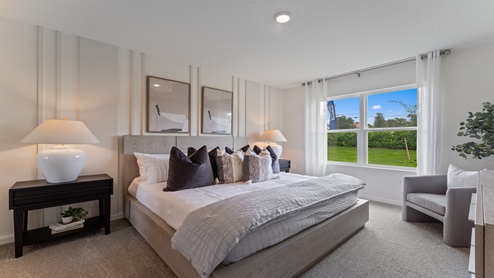 Spacious primary bedroom with king size bed, carpet flooring, natural lighting.