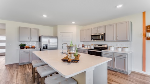 Kitchen with island seating, quartz counters, spacious pantry and stainless steel appliances.