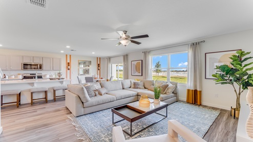 Living area with luxury vinyl plank flooring, couch seating, entertainment system and natural lighting.