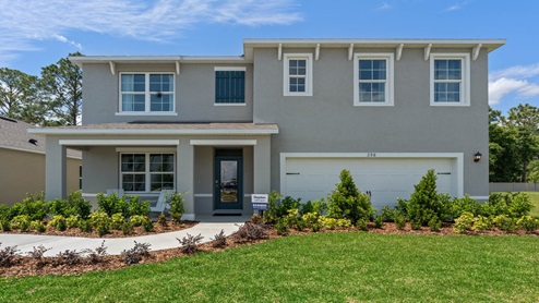 Two-story new home with driveway, large windows, and grassy front yard.
