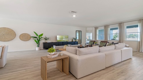Living area with couch seating, entertainment system and natural lighting.