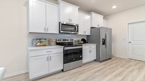 Kitchen with tall cabinetry, appliances, walk in pantry and Luxury vinyl plank flooring.