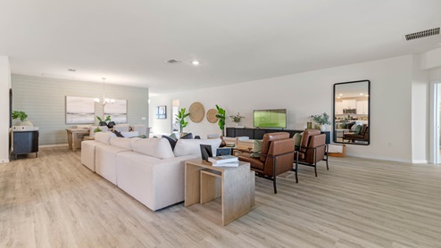 Living area with couch seating, entertainment system and natural lighting.