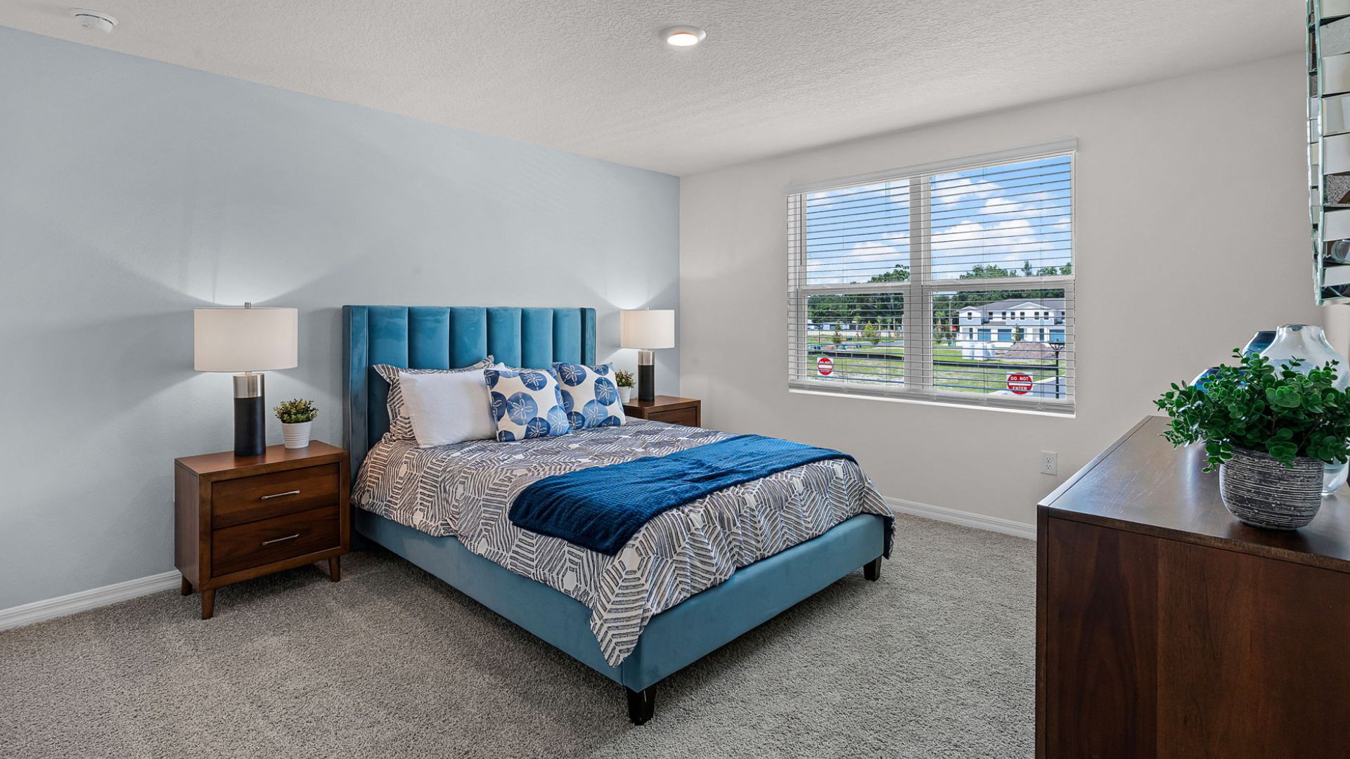 Spacious primary bedroom with king size bed, carpet flooring, natural lighting.