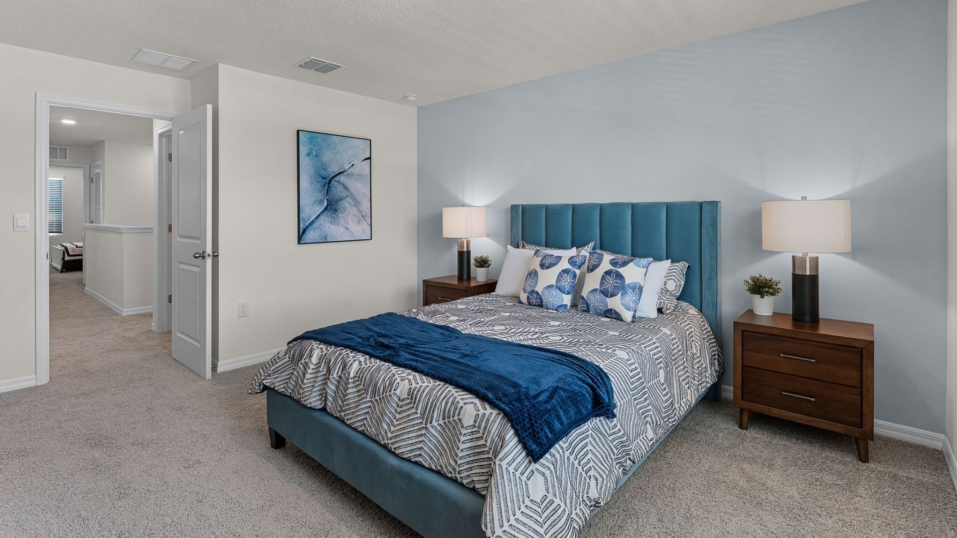 Spacious primary bedroom with king size bed, carpet flooring, natural lighting.