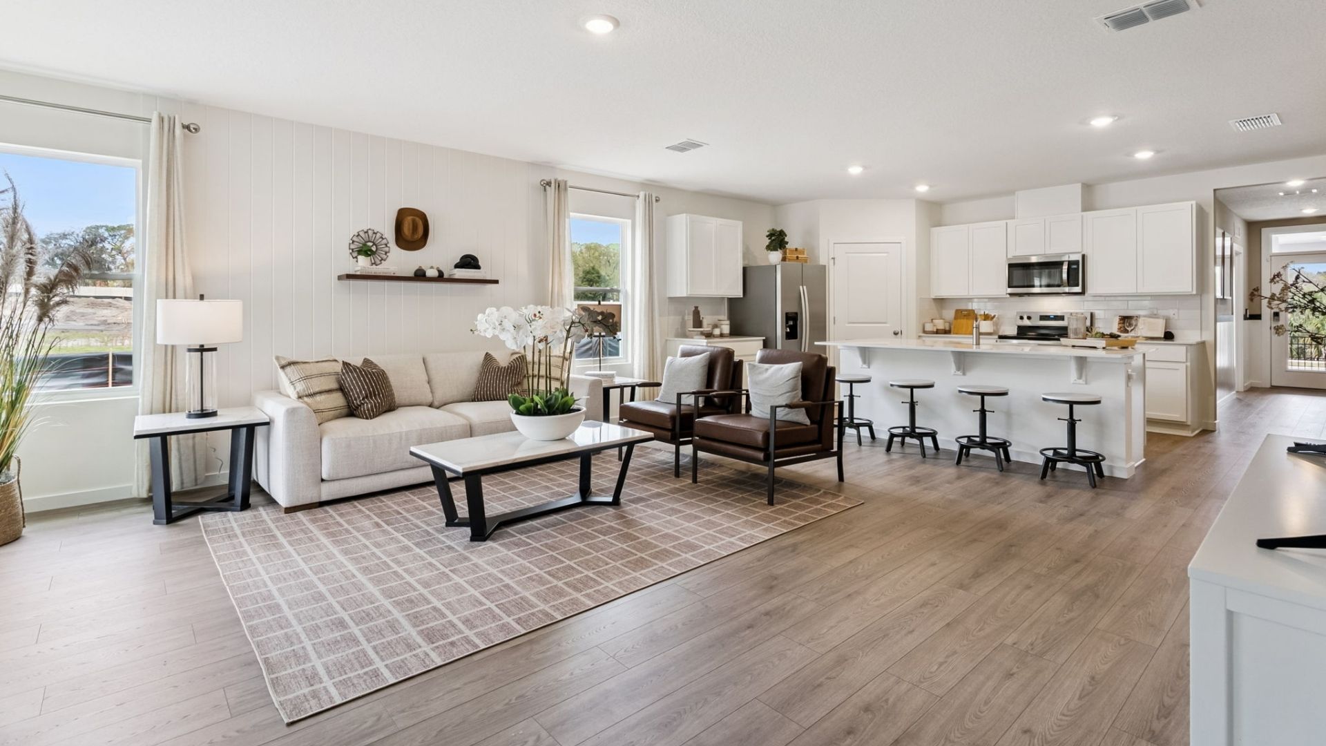 Kitchen with island seating, quartz counters, spacious pantry and stainless steel appliances.