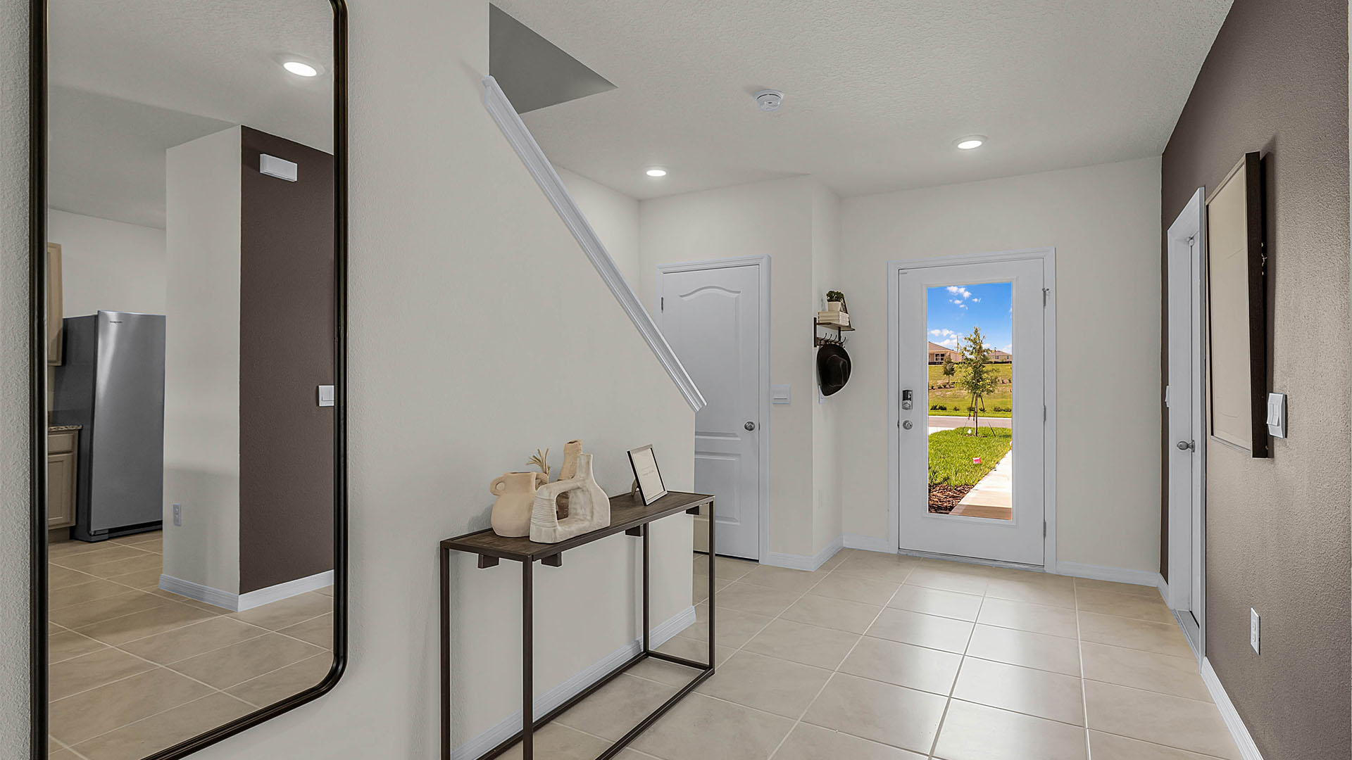 Home entryway with tile flooring, overseeing staircase and access to garage.