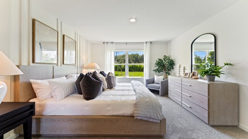 Spacious primary bedroom with king size bed, carpet flooring, natural lighting and a walk in closet.