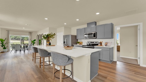 Kitchen with island seating, granite counters, spacious pantry and stainless-steel appliances.