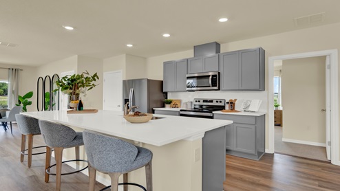 Kitchen with island seating, granite counters, spacious pantry and stainless-steel appliances.