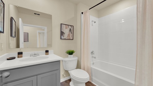 Modern bathroom with single bowl sink, granite vanity, wall mirror, cabinets and toilet.