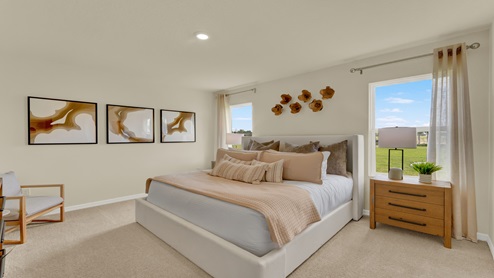 Spacious primary bedroom with king size bed, carpet flooring, natural lighting and a walk in closet.