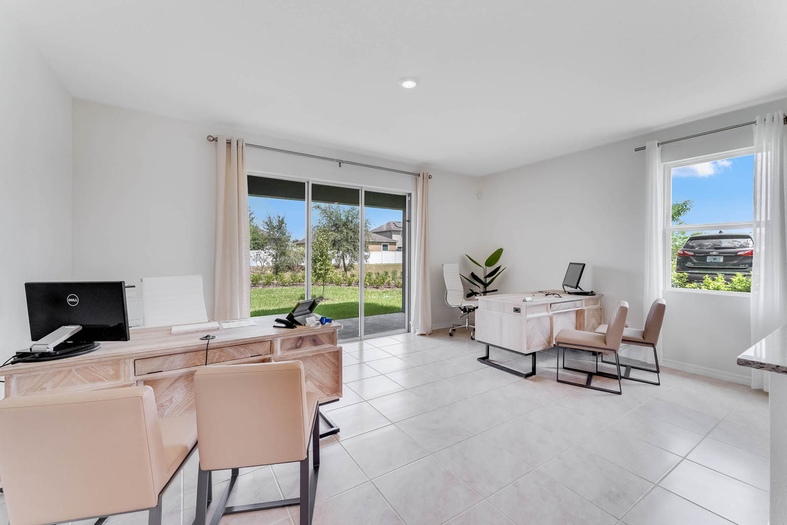 Great room staged for sales office with two large desks and chairs and patio doors to covered patio