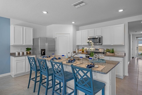 Kitchen with island and white cabinets with fridge and stove
