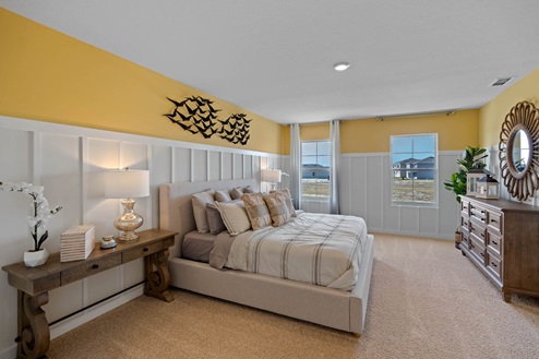 Primary bedroom with bed, vanity, vanity mirror and side table