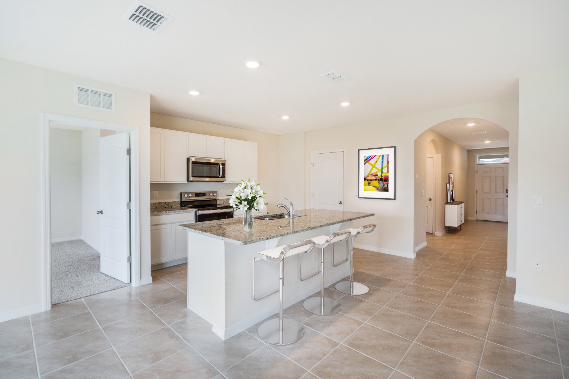 Kitchen island with barstools and a door facing the primary bedroom.