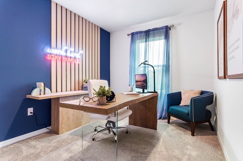 Guest room staged as an office with desk and seating