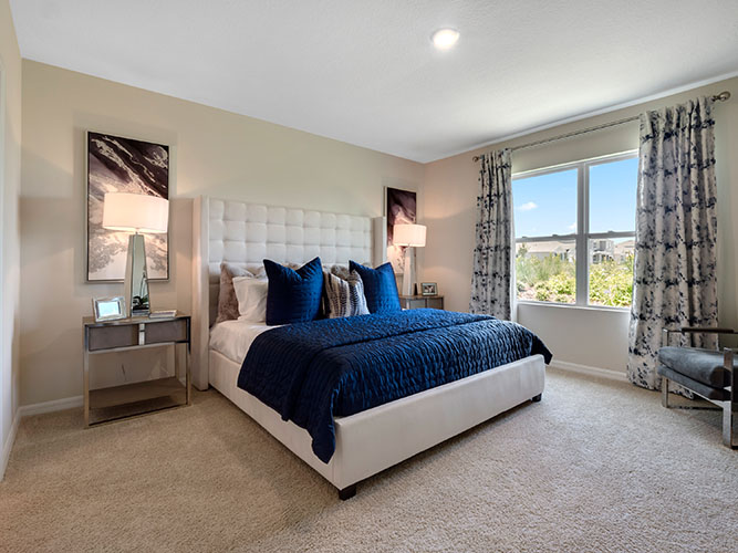 Primary bedroom with two windows and carpet flooring
