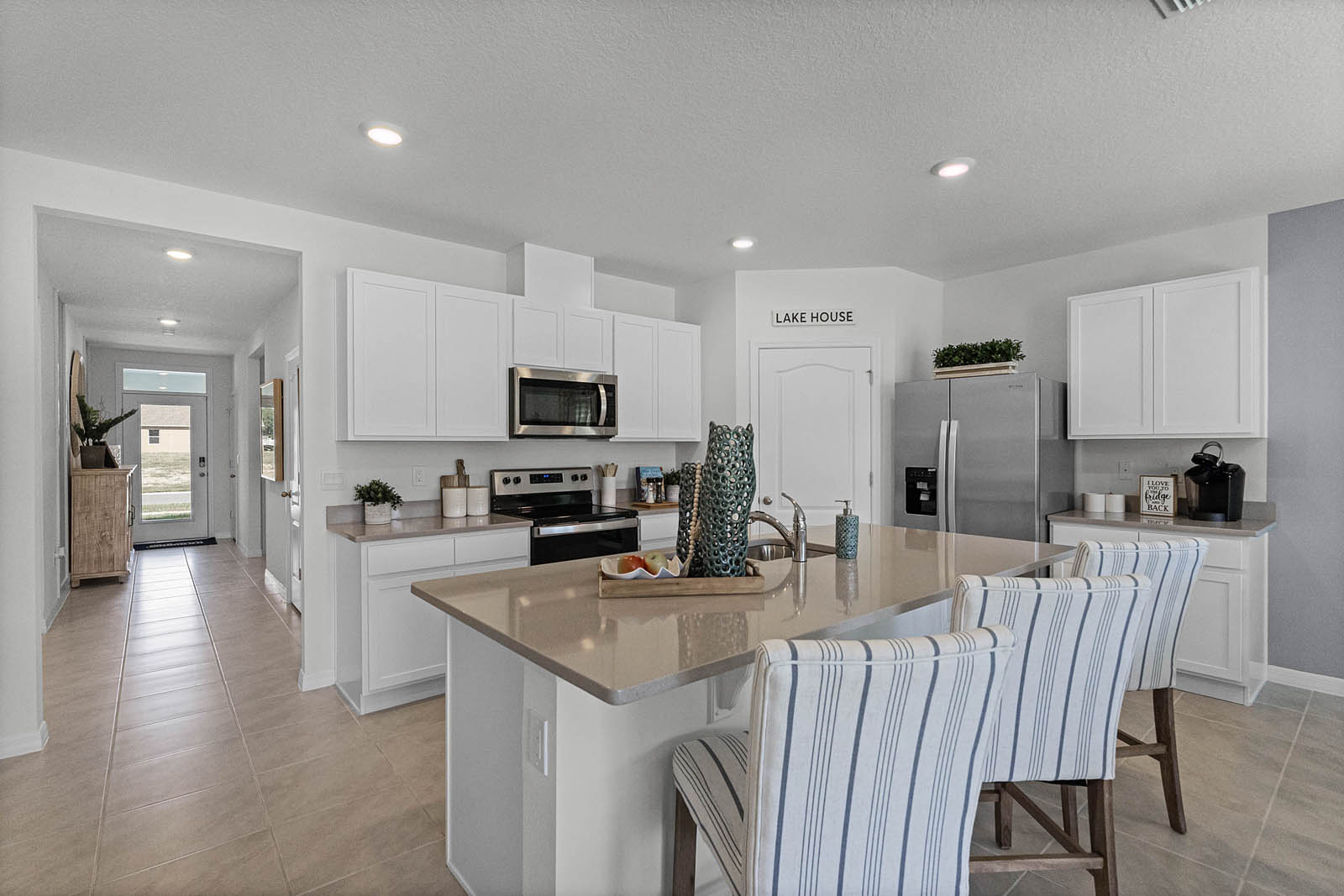 Kitchen Island with stainless steel appliances and view of the entry way of the home.
