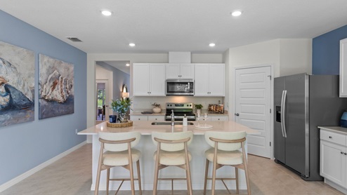 Open kitchen area with barstools and stainless steel appliances