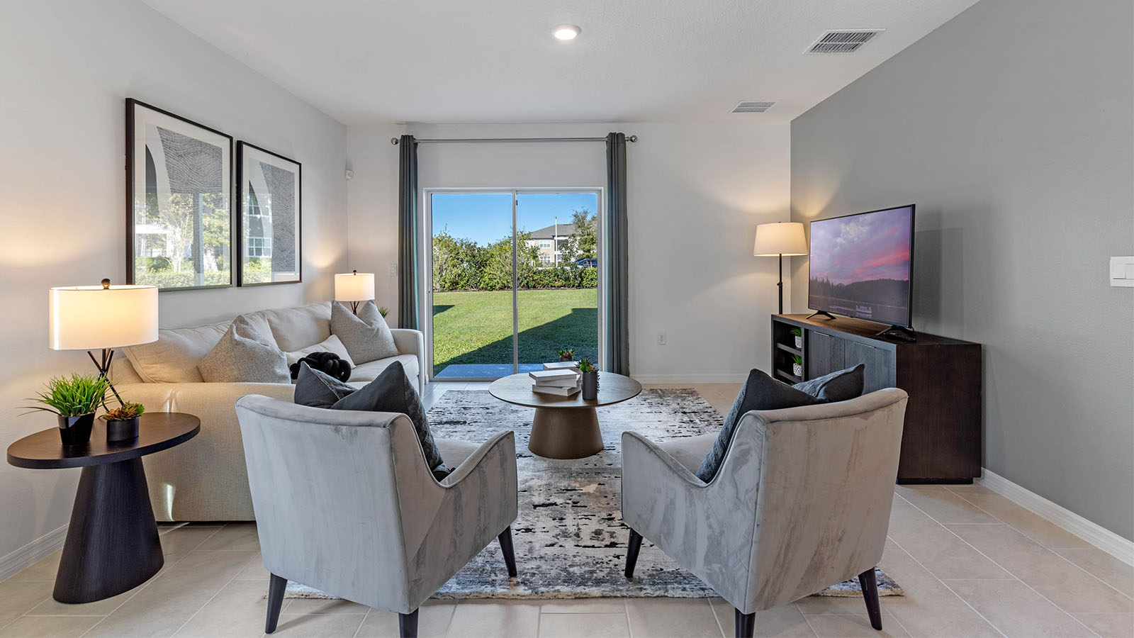 Living Room with sofa, two chairs, and tv stand overlooking patio with sliding glass doors