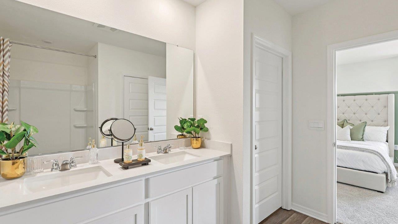 Primary bedroom with dual vanity sink and decor