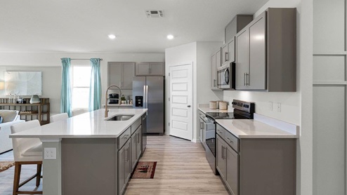 Spacious kitchen with large island, quartz counter tops and sleek gray cabinets