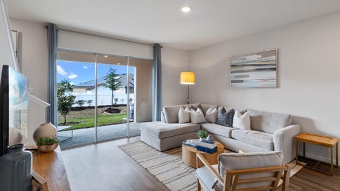 Living room with white sectional, area rig, and view to patio with sliding glass doors