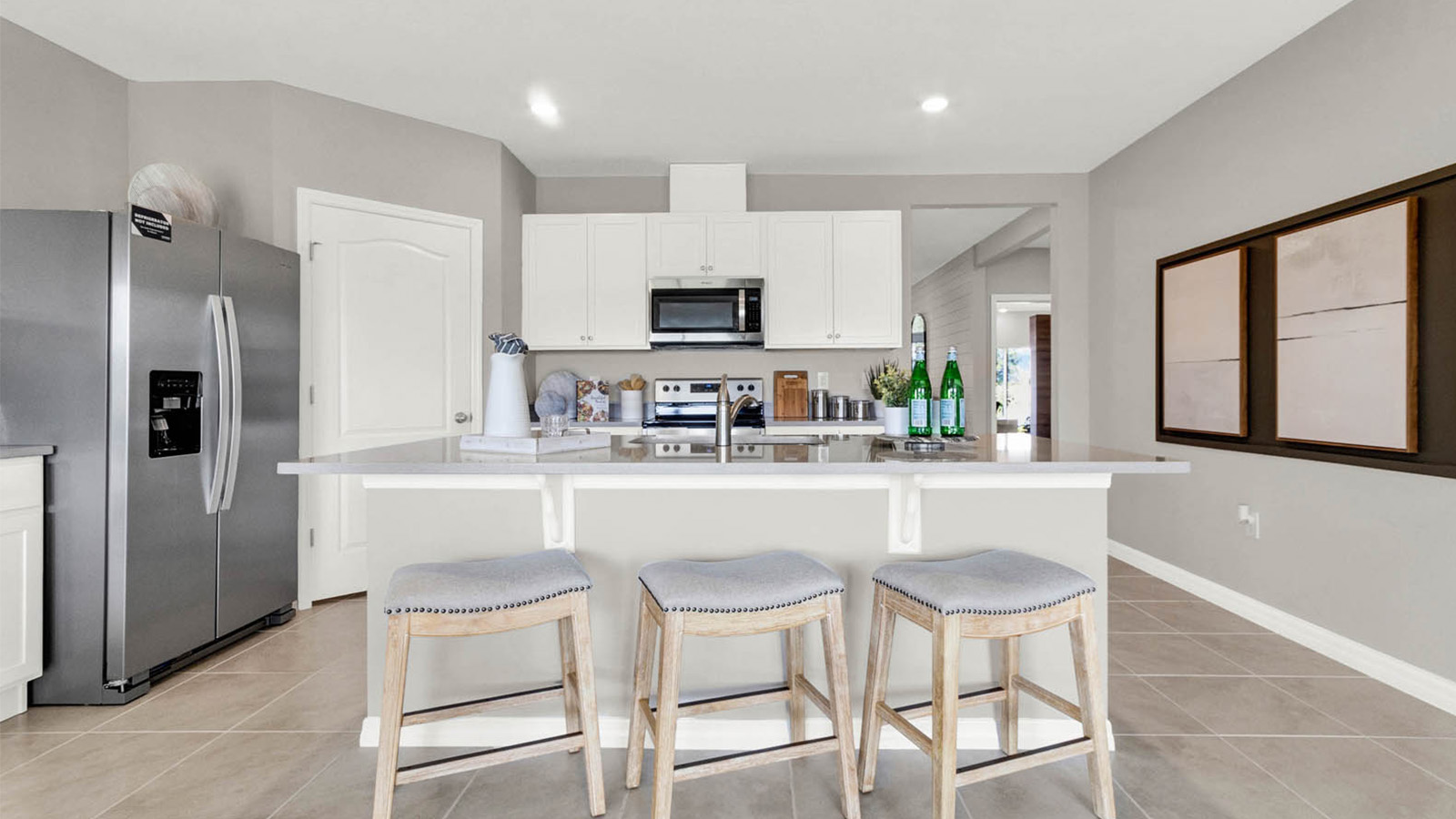 View of the kitchen island with barstools and the refrigerator