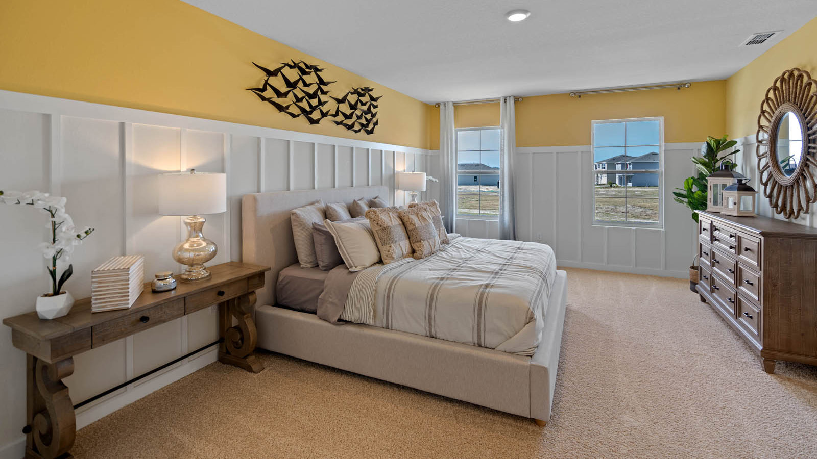Primary bedroom with bed, vanity, vanity mirror and side table