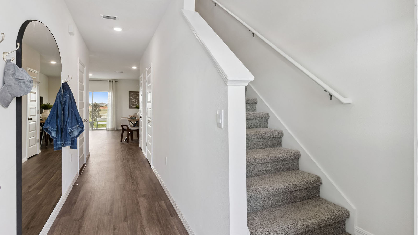 Entrance to the open living area with large mirror and stairs to second floor