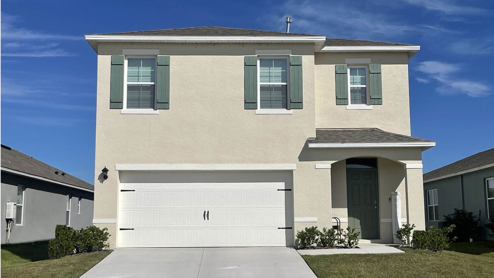 Front view of single-family two-story home with two-car garage with shutters and stone accents