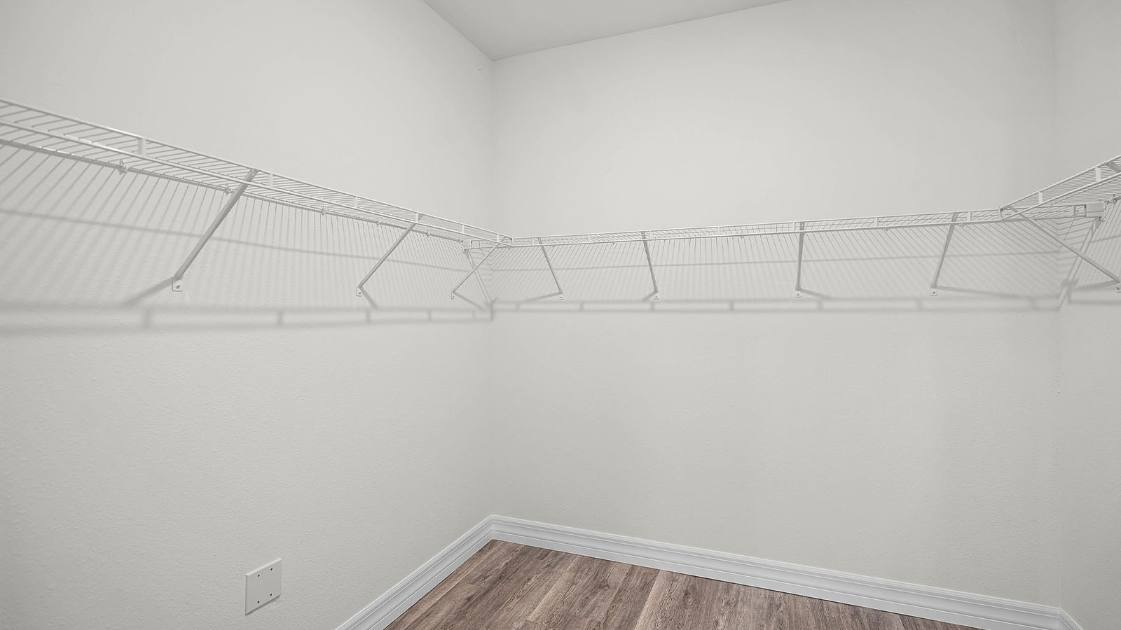 Primary walk in closet with luxury vinyl planks