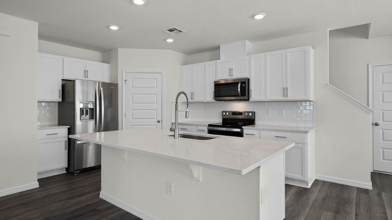 Kitchen with stainless steel appliances with stairs behind the kitchen