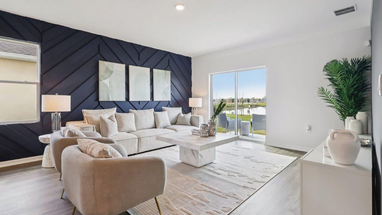 Living room decorated with couch, chairs, and wall art with a view to the backyard