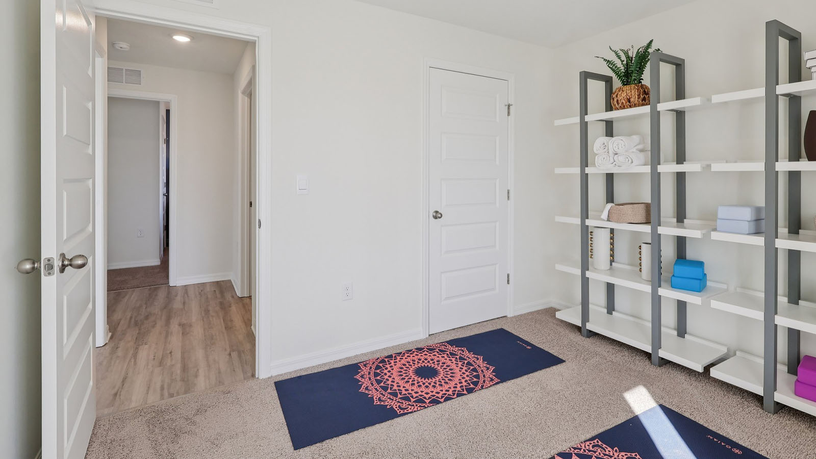 Guest bedroom staged as yoga room with fitness equipment on shelves