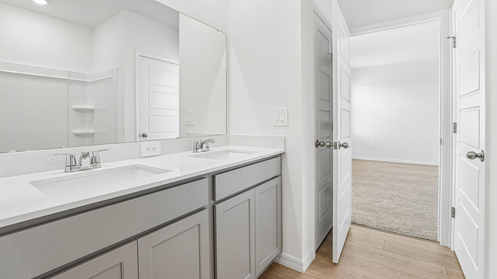 Primary bathroom with two vanity sinks and a closet