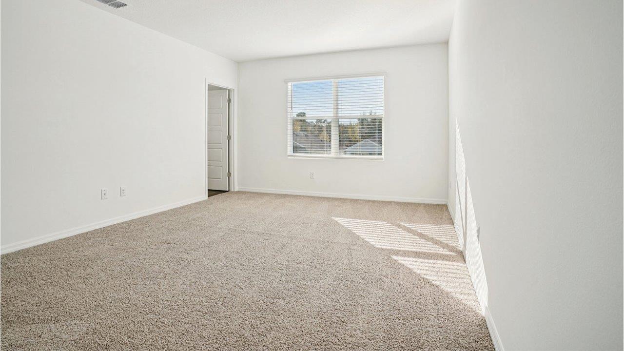primary bedroom with window and door to bathroom
