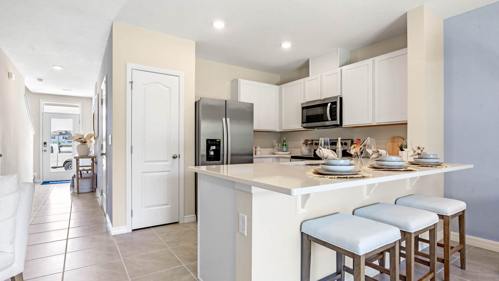 Kitchen with island and barstools with view to entryway