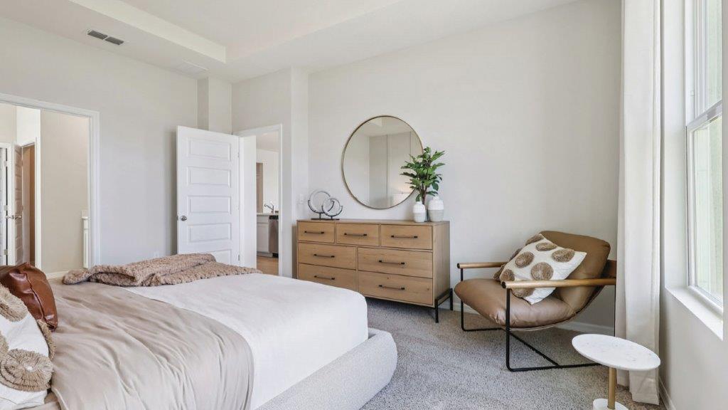 primary bedroom with bed, dresser and chair