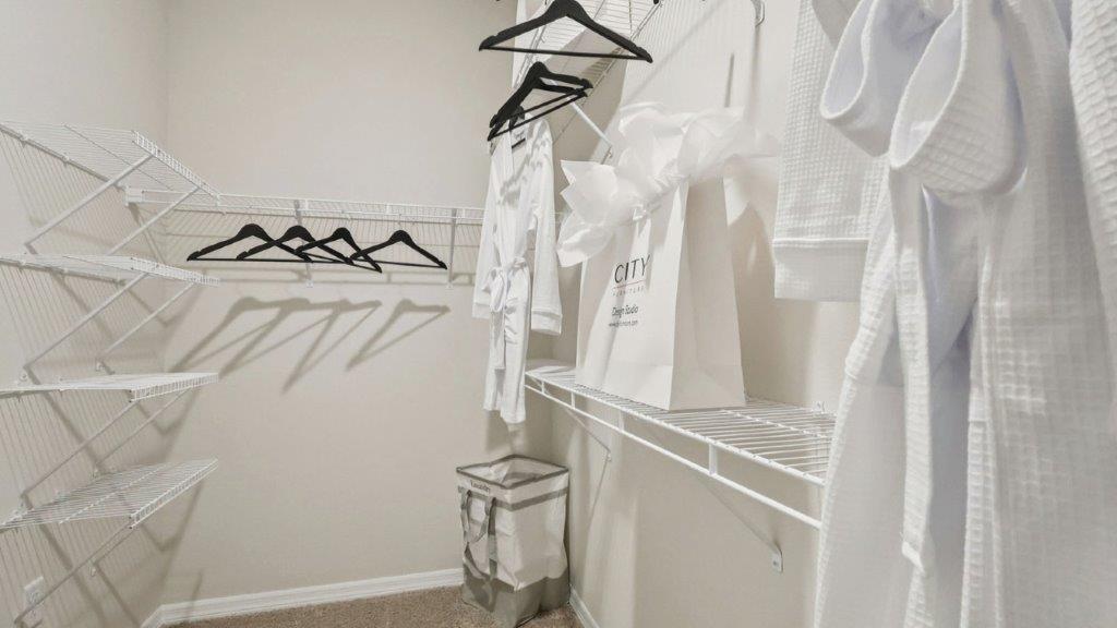 primary bedroom walk in closet with shelves