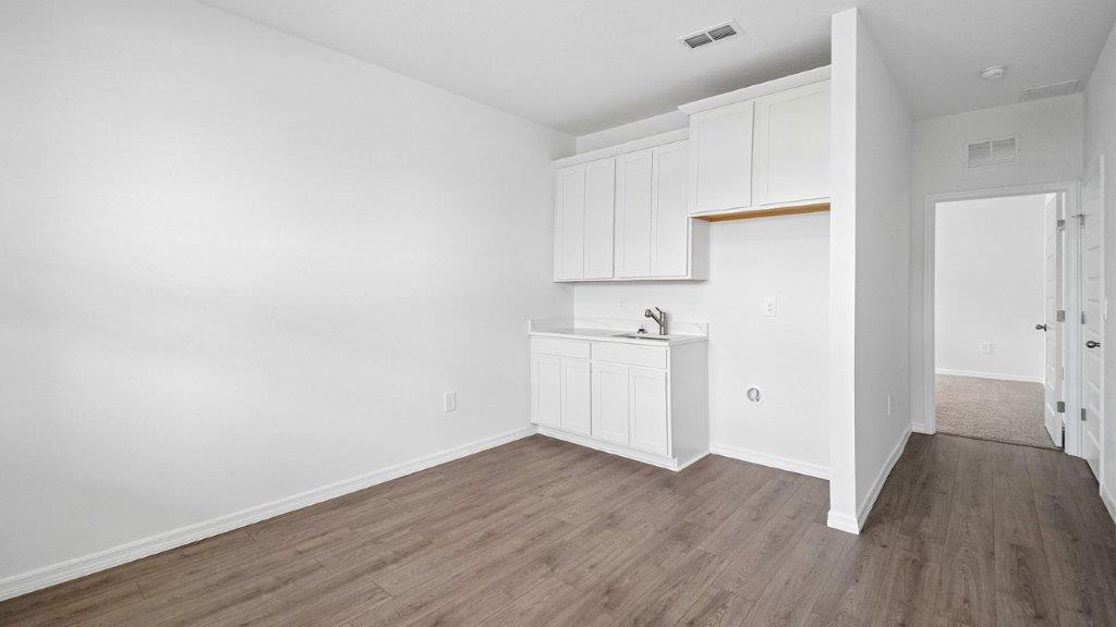 Downstairs bedroom with luxury vinyl planks and a small kitchen set up