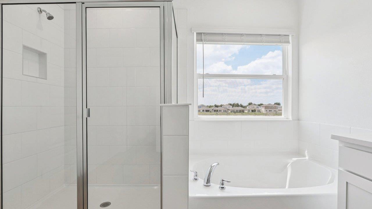 walk in shower with a tub to the right of the shower